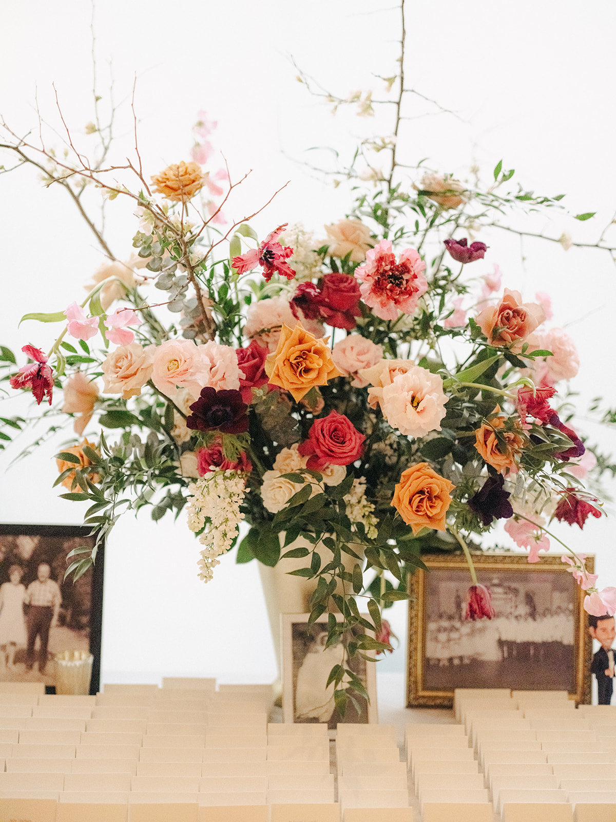 A lush garden-style arrangement featuring a mix of vibrant roses, lisianthus, and greenery, complemented by delicate branches and vintage accents.