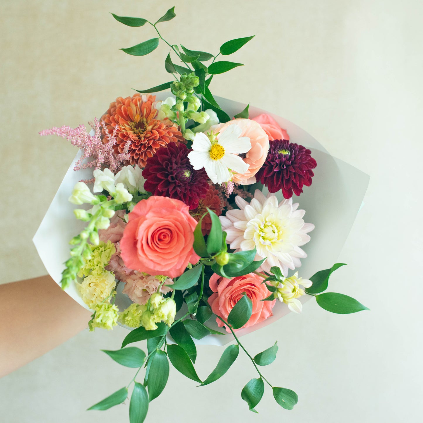 Bouquet of colorful flowers held by a person against a light background