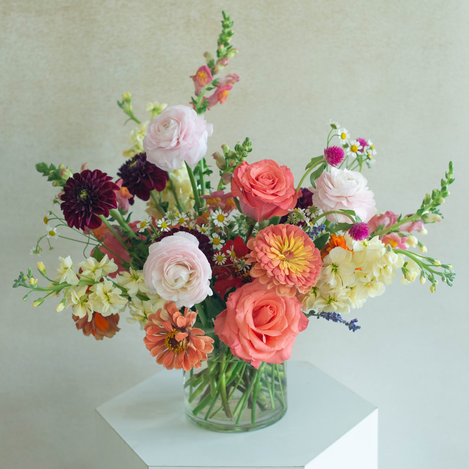 Bouquet of colorful flowers in a clear vase on a light background