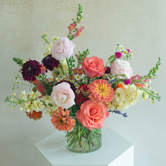 Bouquet of colorful flowers in a clear vase on a light background