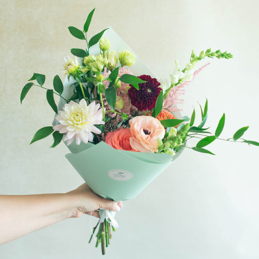 Bouquet of flowers held by a hand against a light background
