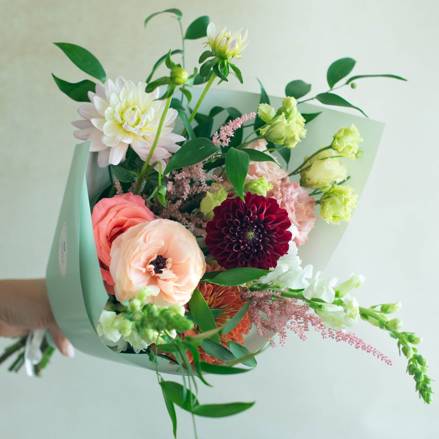 Bouquet of flowers held by a hand with a light background