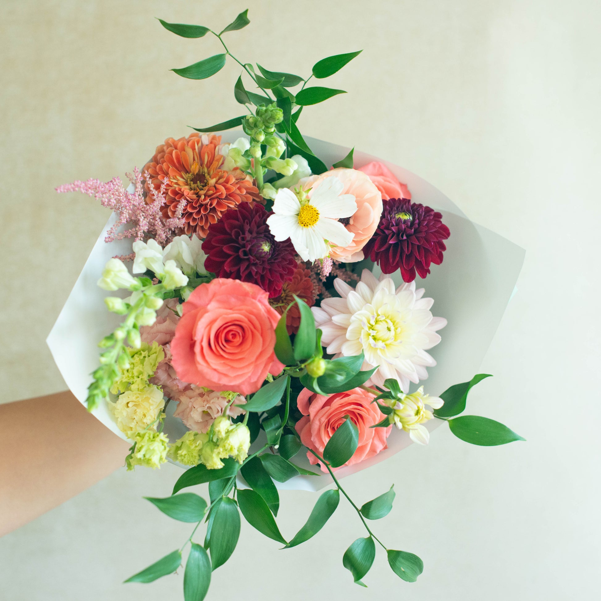Bouquet of colorful flowers held by a person against a light background