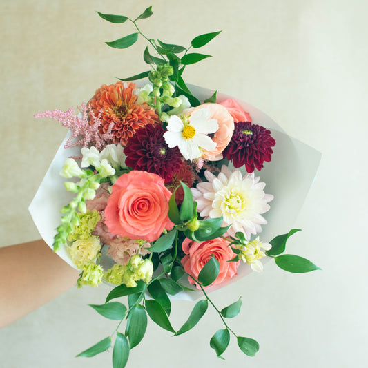 Bouquet of colorful flowers held by a person against a light background