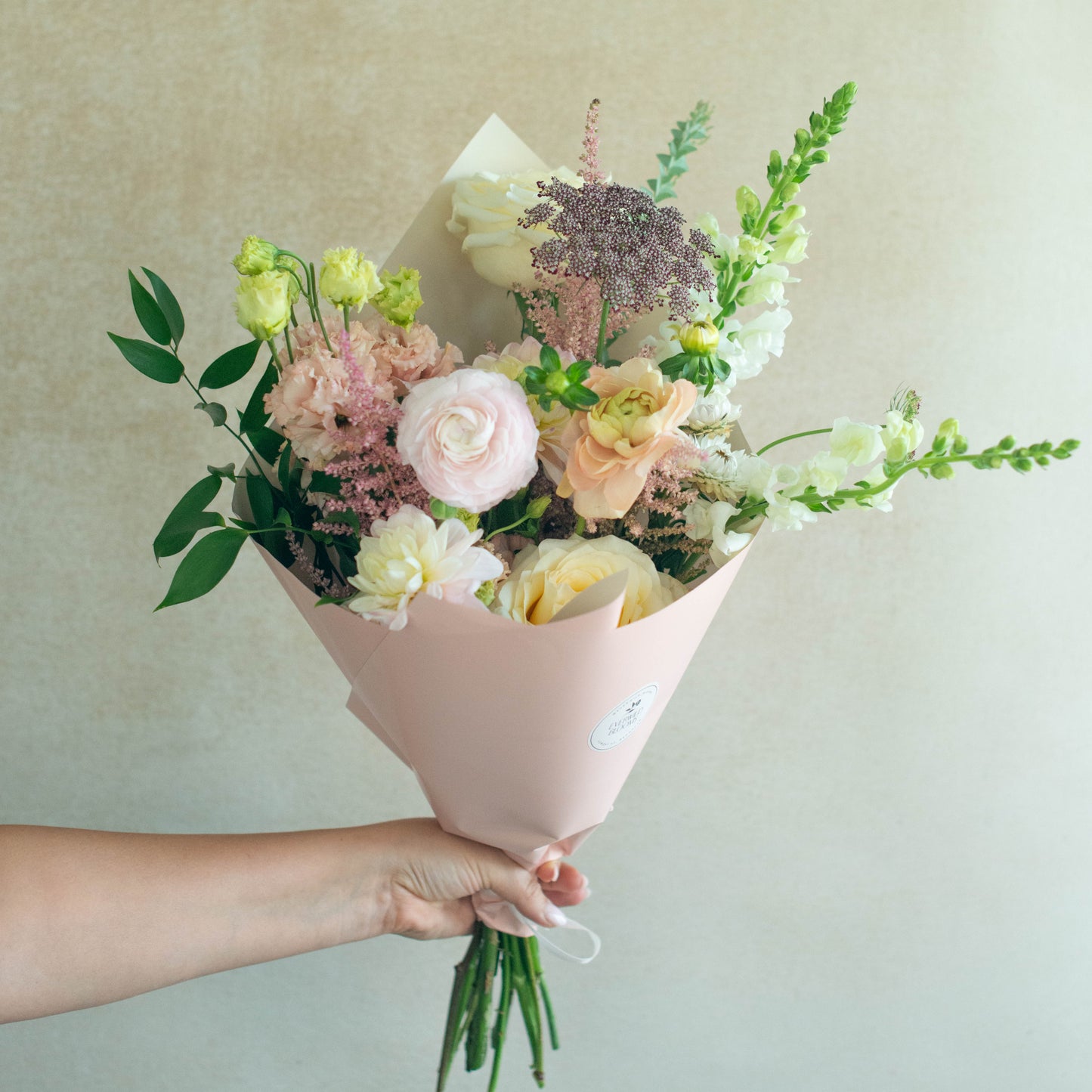 Bouquet of flowers held by a person against a plain background