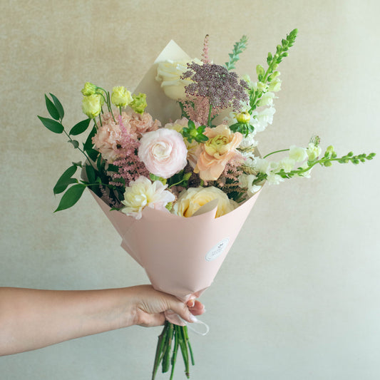 Bouquet of flowers held by a person against a plain background