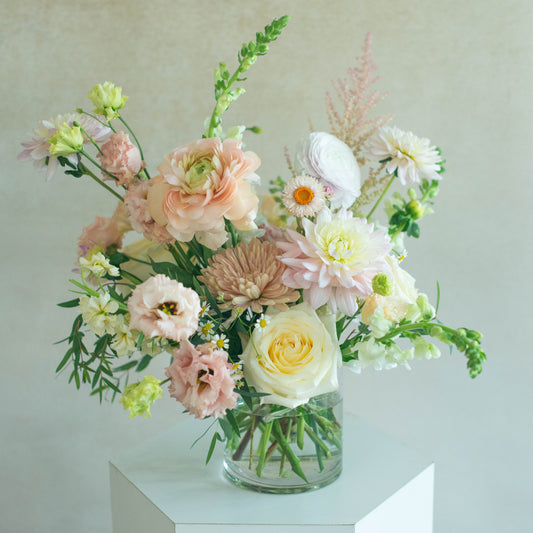 Bouquet of flowers in a clear vase on a white surface with a light gray background
