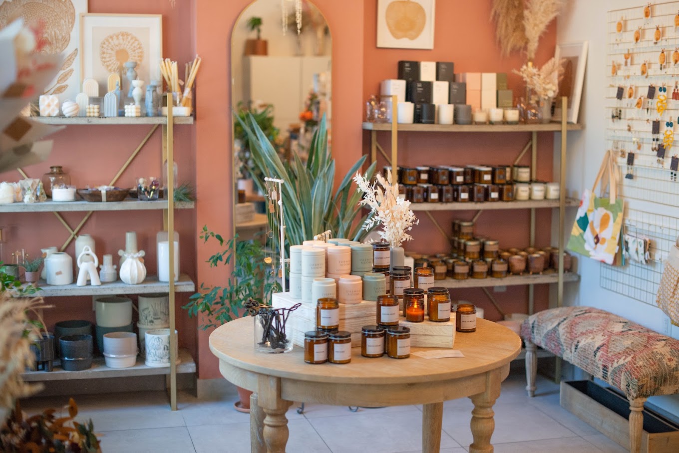 A cozy boutique interior featuring a curated display of candles, home decor, and dried florals against warm terracotta walls, creating a charming and inviting atmosphere.