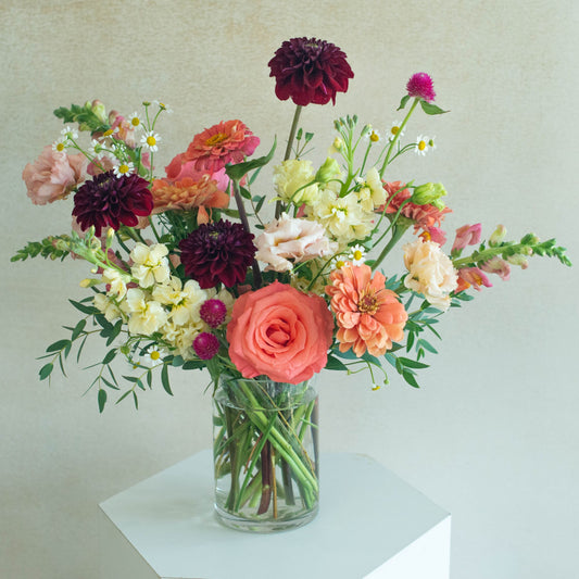 Bouquet of flowers in a clear vase on a light surface with a neutral background